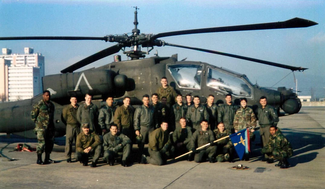 Shannon Huffman Polson with her Apache company in front of an AH-64 Apache helicopter, 2000