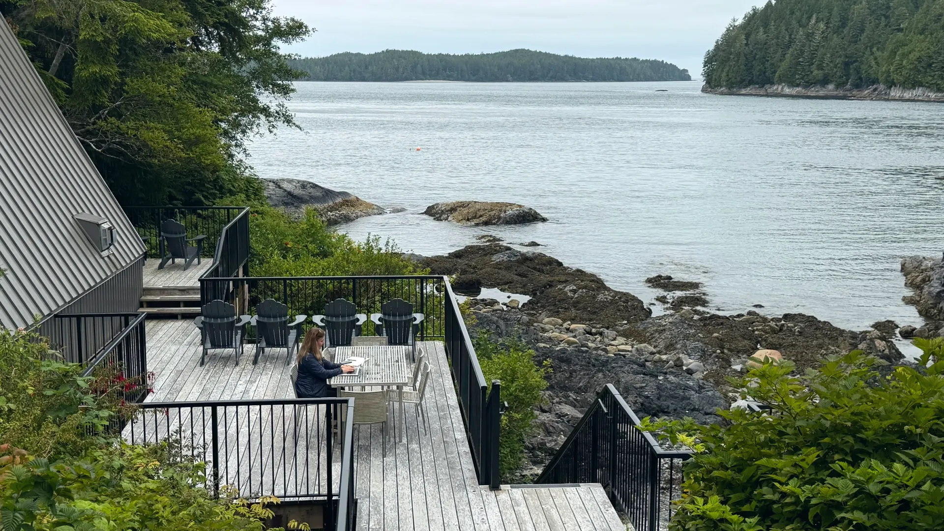 Shannon Huffman Polson writing at a table on a deck above the water